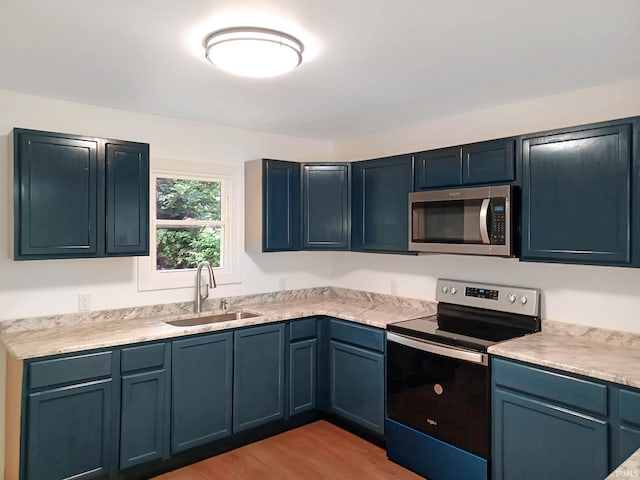 kitchen with light hardwood / wood-style floors, sink, blue cabinets, and stainless steel appliances