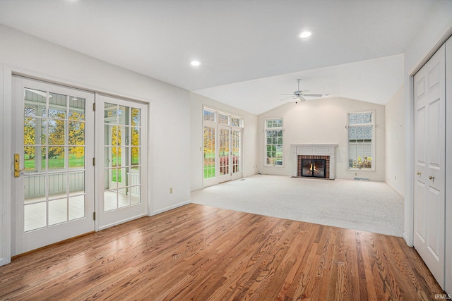 unfurnished living room featuring hardwood / wood-style flooring, ceiling fan, vaulted ceiling, and a brick fireplace