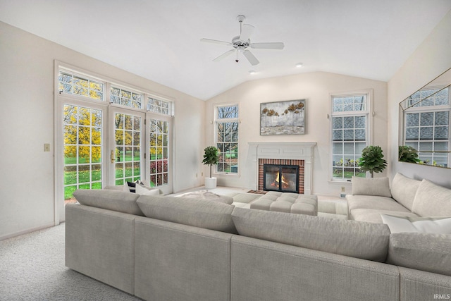 carpeted living room with ceiling fan, vaulted ceiling, and a brick fireplace