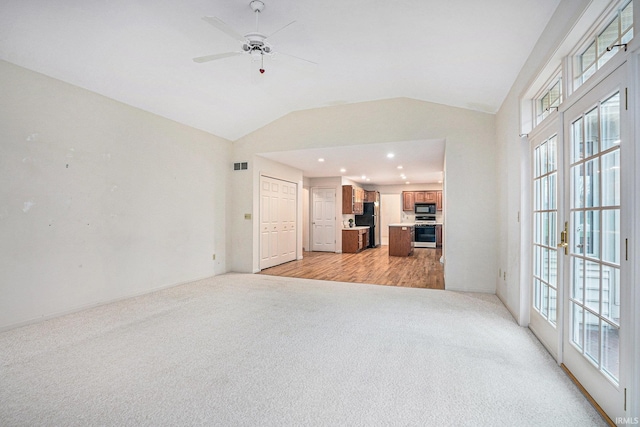 unfurnished living room with french doors, ceiling fan, light hardwood / wood-style flooring, and lofted ceiling