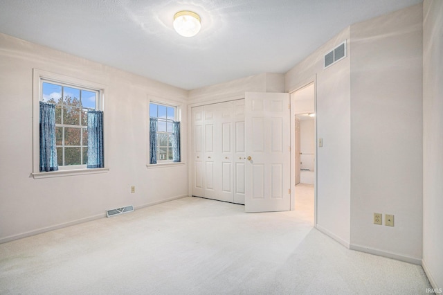 unfurnished bedroom with light colored carpet and a closet