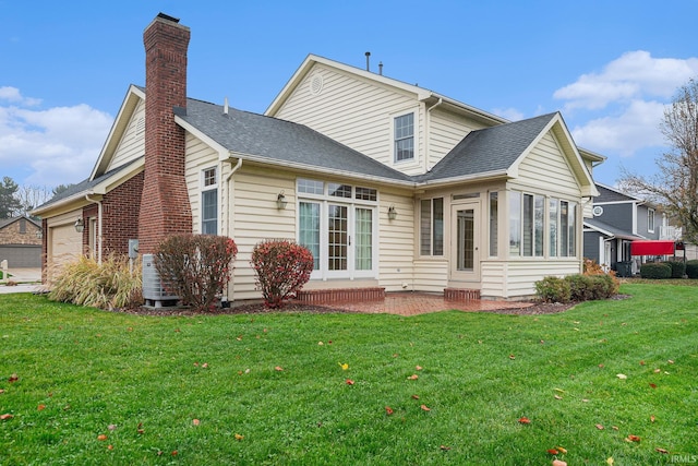 rear view of house with a lawn, a sunroom, and a garage