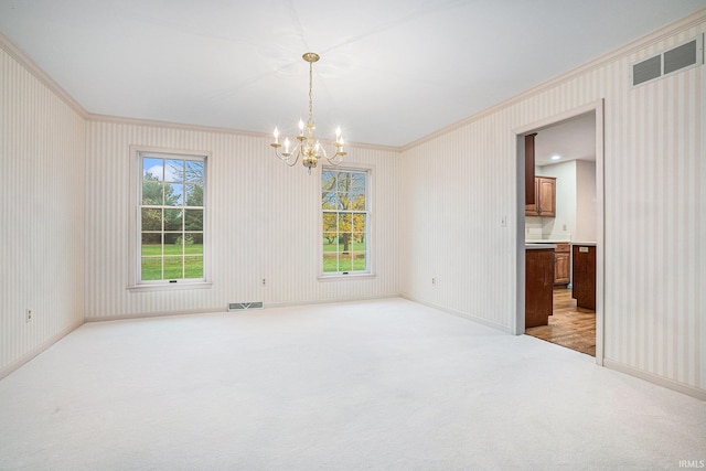 spare room featuring ornamental molding, light carpet, and a chandelier