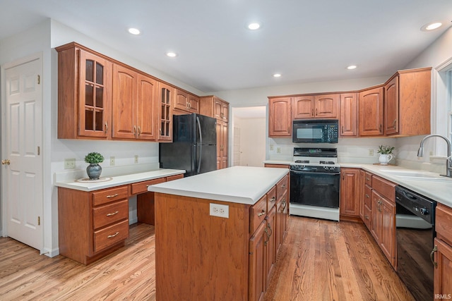 kitchen featuring black appliances, a center island, sink, and light hardwood / wood-style flooring