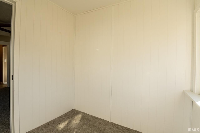 unfurnished room with carpet and wooden walls