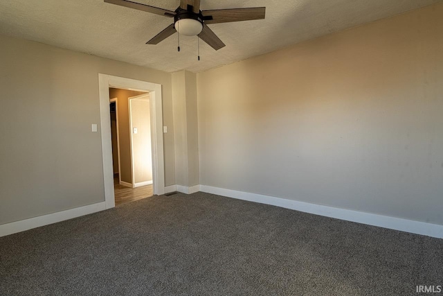 empty room with dark colored carpet, ceiling fan, and a textured ceiling