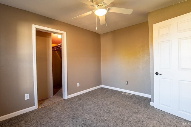 unfurnished bedroom with carpet flooring, ceiling fan, a closet, and a spacious closet