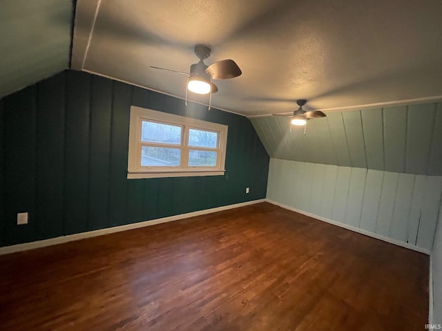 additional living space featuring a textured ceiling, lofted ceiling, ceiling fan, and dark hardwood / wood-style floors