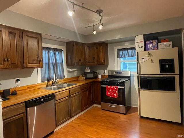 kitchen featuring butcher block countertops, sink, light hardwood / wood-style floors, and appliances with stainless steel finishes