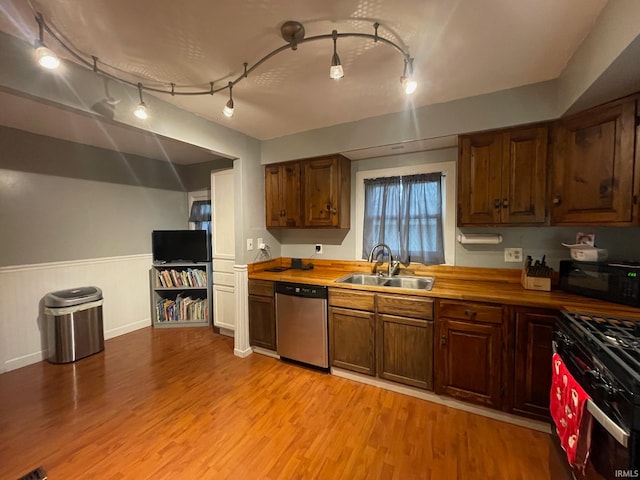 kitchen featuring track lighting, black appliances, sink, light hardwood / wood-style flooring, and butcher block countertops