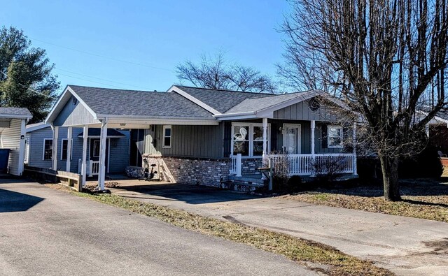 208 Sycamore St, Loogootee, IN 47553 - ranch-style house with a porch, roof with shingles, driveway, and board and batten siding