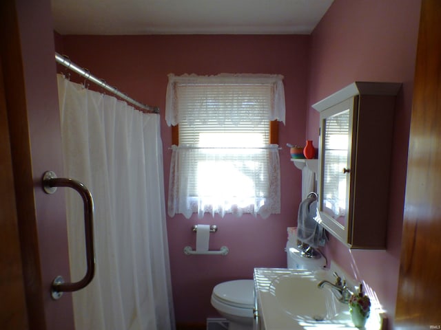 bathroom with walk in shower, a wealth of natural light, sink, and toilet