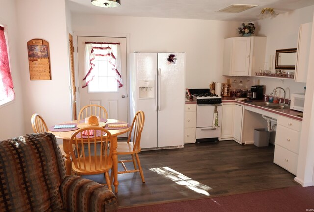 208 Sycamore St, Loogootee, IN 47553 - kitchen with white appliances, a sink, white cabinetry, dark wood finished floors, and dark countertops