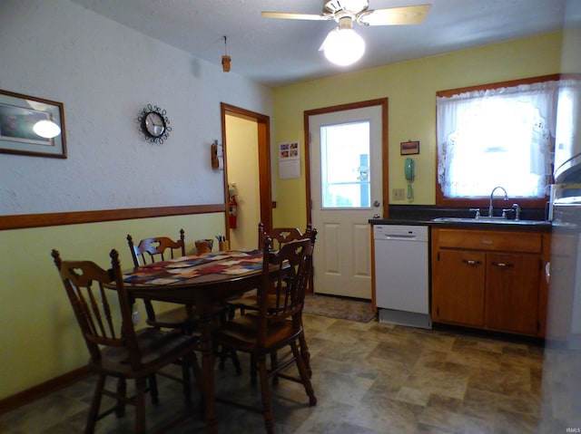 208 Sycamore St, Loogootee, IN 47553 - kitchen with dishwasher, brown cabinetry, dark countertops, ceiling fan, and a sink