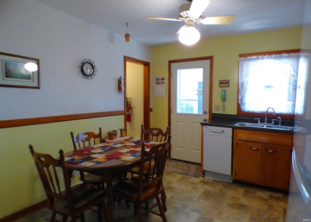 208 Sycamore St, Loogootee, IN 47553 - kitchen featuring dishwasher, a sink, brown cabinetry, ceiling fan, and dark countertops