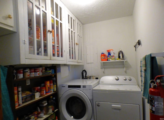 laundry room with washer and clothes dryer, cabinets, and a textured ceiling