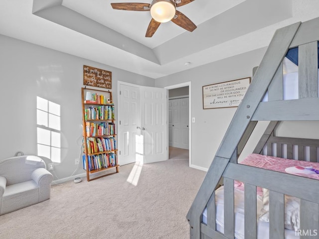 carpeted bedroom featuring ceiling fan and a raised ceiling