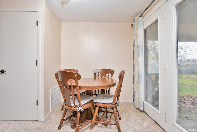 carpeted dining room with a textured ceiling