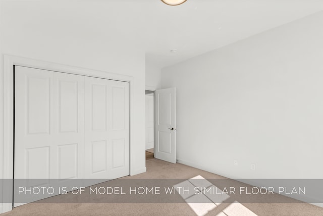 unfurnished bedroom with light colored carpet and a closet