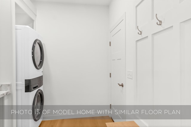 clothes washing area with stacked washer / dryer and cabinets