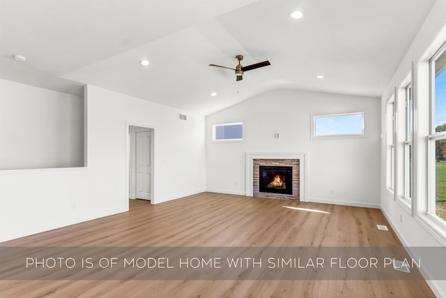 unfurnished living room featuring ceiling fan, a fireplace, vaulted ceiling, and light wood-type flooring