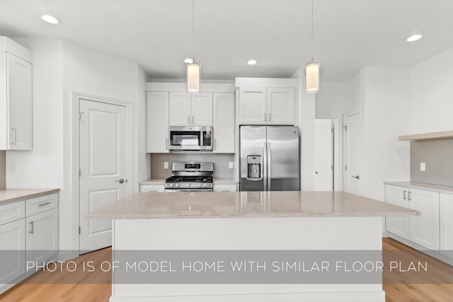 kitchen with white cabinetry, a center island, stainless steel appliances, light hardwood / wood-style flooring, and decorative light fixtures