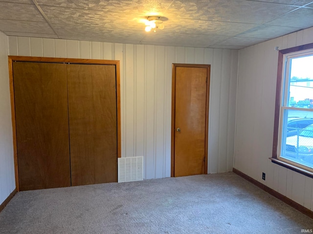 unfurnished bedroom with wood walls, a closet, and carpet floors