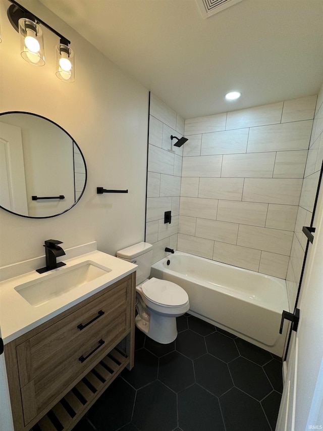 full bathroom with tile patterned flooring, vanity, tiled shower / bath combo, and toilet