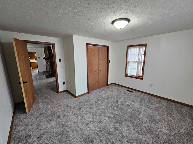 unfurnished bedroom with a closet, a textured ceiling, and dark colored carpet