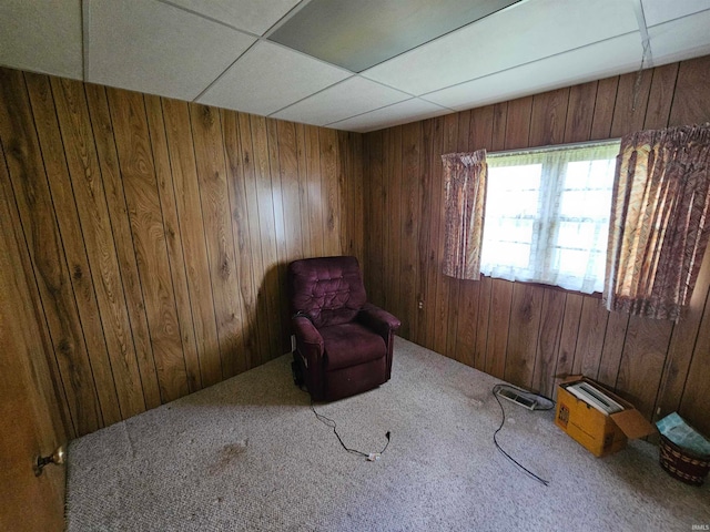 unfurnished room with carpet flooring, a paneled ceiling, and wooden walls