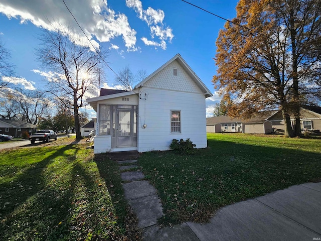 view of home's exterior with a sunroom and a yard