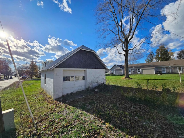 view of side of home featuring a garage, an outdoor structure, and a lawn