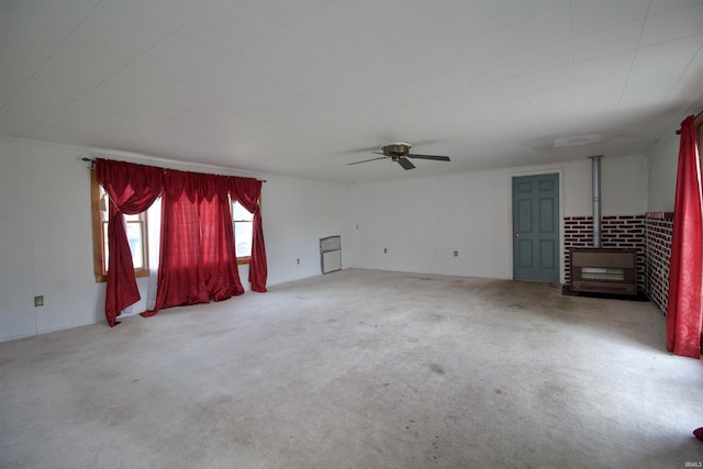 carpeted empty room with ceiling fan and a wood stove