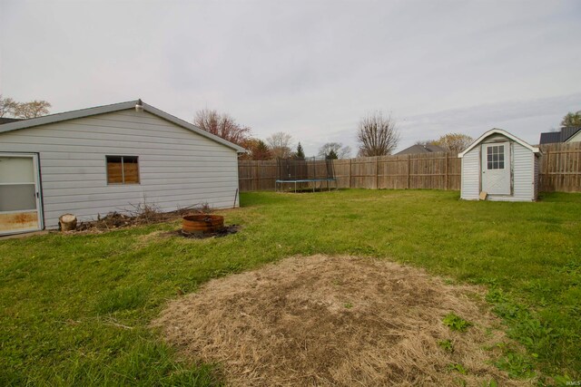 view of yard featuring a trampoline, a shed, and an outdoor fire pit