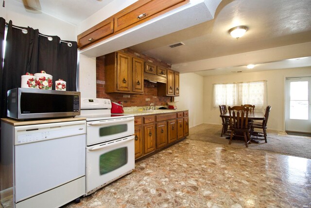 kitchen with tasteful backsplash, light carpet, sink, and white appliances