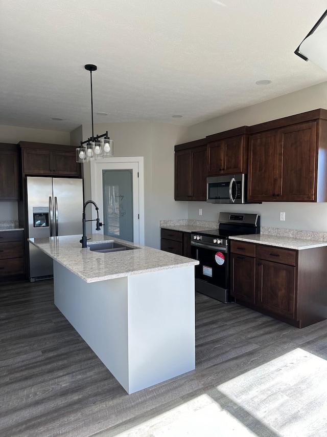 kitchen featuring sink, stainless steel appliances, dark hardwood / wood-style floors, decorative light fixtures, and a center island with sink