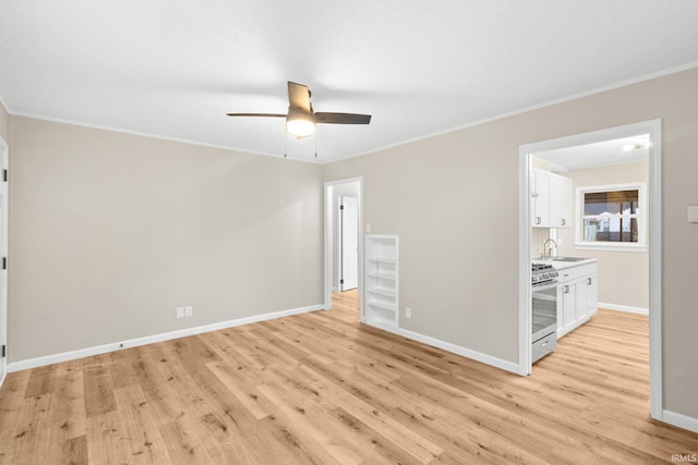 empty room with ceiling fan, light hardwood / wood-style floors, crown molding, and sink