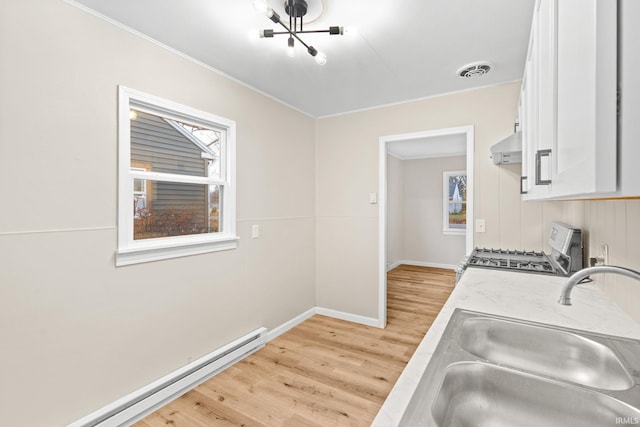 kitchen featuring sink, stainless steel stove, baseboard heating, light hardwood / wood-style flooring, and white cabinets