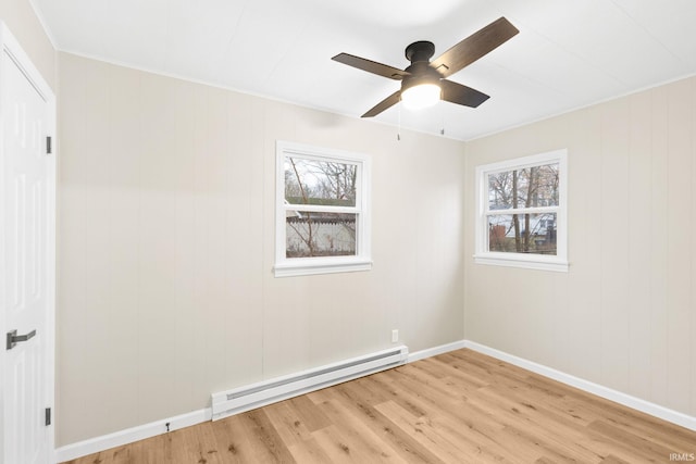 spare room featuring light hardwood / wood-style floors, baseboard heating, crown molding, and ceiling fan