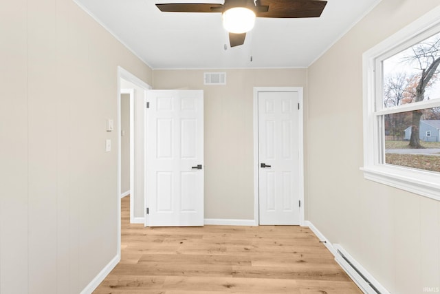 unfurnished bedroom featuring ceiling fan, crown molding, a baseboard radiator, and light wood-type flooring