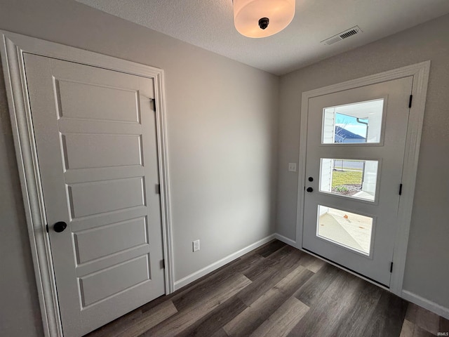 doorway with a textured ceiling and dark hardwood / wood-style floors