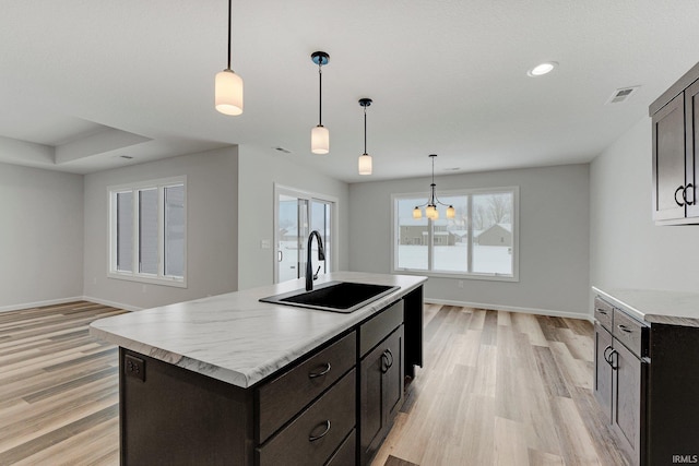 15384 Brimwillow Dr, Huntertown, IN 46748 - kitchen featuring light wood finished floors, a sink, baseboards, light countertops, and an island with sink