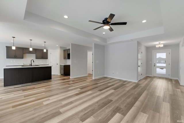 15384 Brimwillow Dr, Huntertown, IN 46748 - unfurnished living room featuring a sink, a tray ceiling, ceiling fan, light wood-type flooring, and recessed lighting