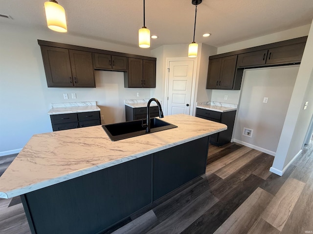 kitchen featuring dark brown cabinetry, decorative light fixtures, dark wood-type flooring, and sink