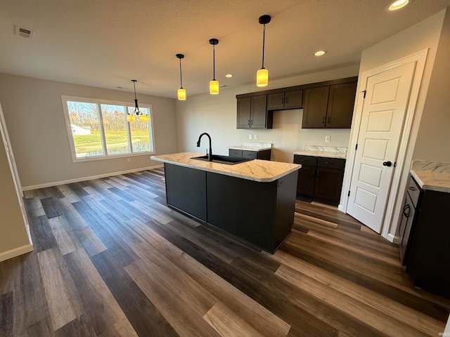 kitchen featuring sink, hanging light fixtures, dark hardwood / wood-style floors, light stone countertops, and dark brown cabinetry