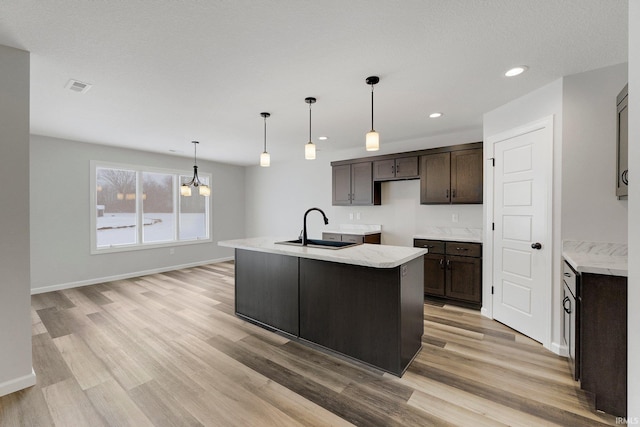 15384 Brimwillow Dr, Huntertown, IN 46748 - kitchen with a sink, dark brown cabinets, light wood-type flooring, a center island with sink, and recessed lighting