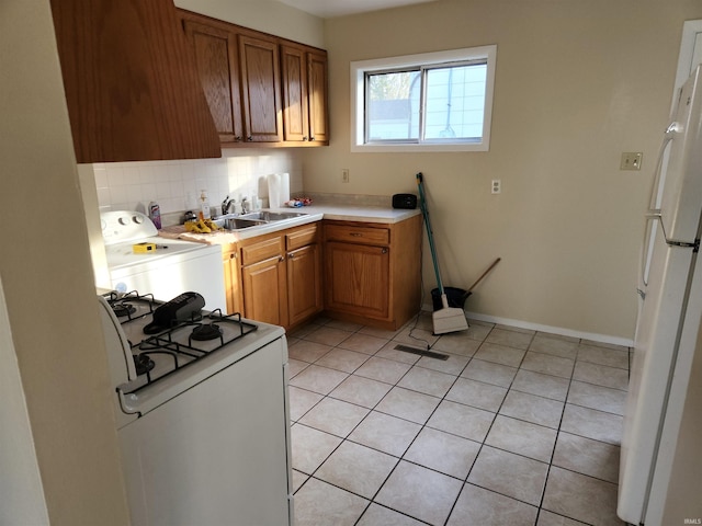 kitchen featuring washer / clothes dryer, sink, light tile patterned floors, and white appliances