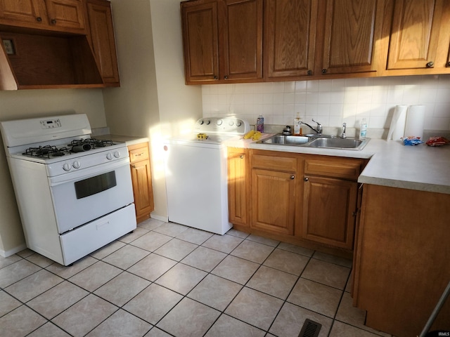 kitchen featuring tasteful backsplash, premium range hood, white gas range, sink, and washer / clothes dryer