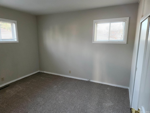 spare room featuring dark carpet and plenty of natural light