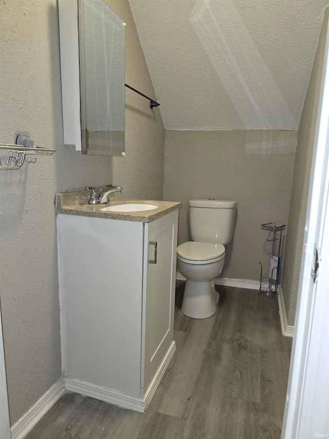 bathroom featuring toilet, vanity, vaulted ceiling, and hardwood / wood-style flooring